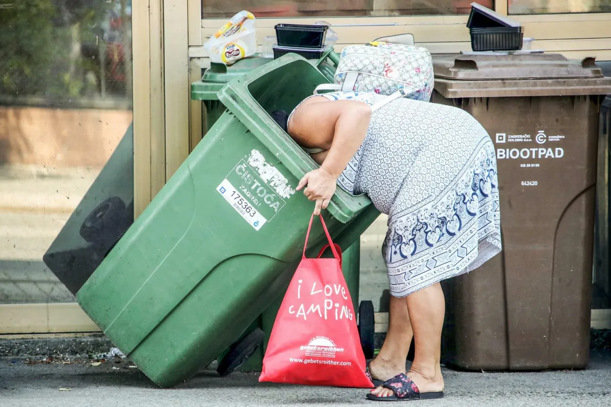 23.07.2021., Zagreb - Ilica. Koliko duboko treba zaroniti glavu u smece ne bi li se pronasla sitnica koja ovoj gospodji puno znaci? Sve je vise ljudi koji kopaju po smecu trazeci nesto sto bi im pomoglo u ovim teskim zivotnim situacijama neimastine. Photo: Sanjin Strukic/PIXSELL